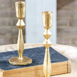 Two gold candle holders on a stack of books with a blurred background