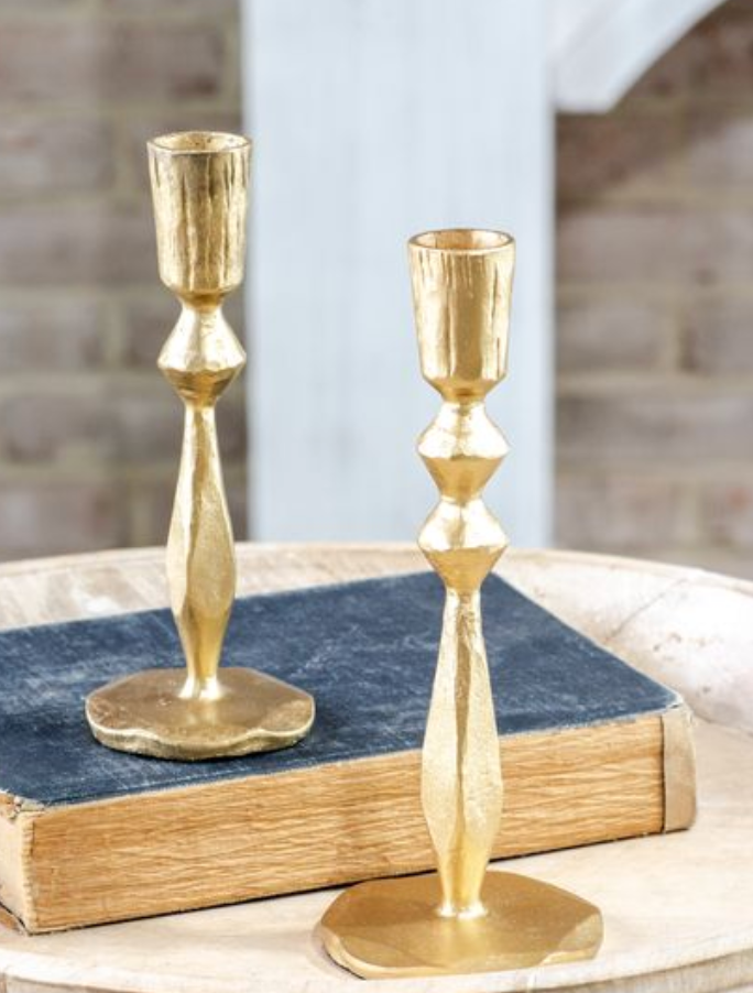 Two gold candle holders on a stack of books with a blurred background