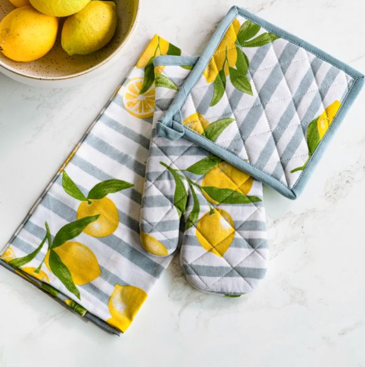 Set of kitchen towels and potholders with lemon design on a white surface.